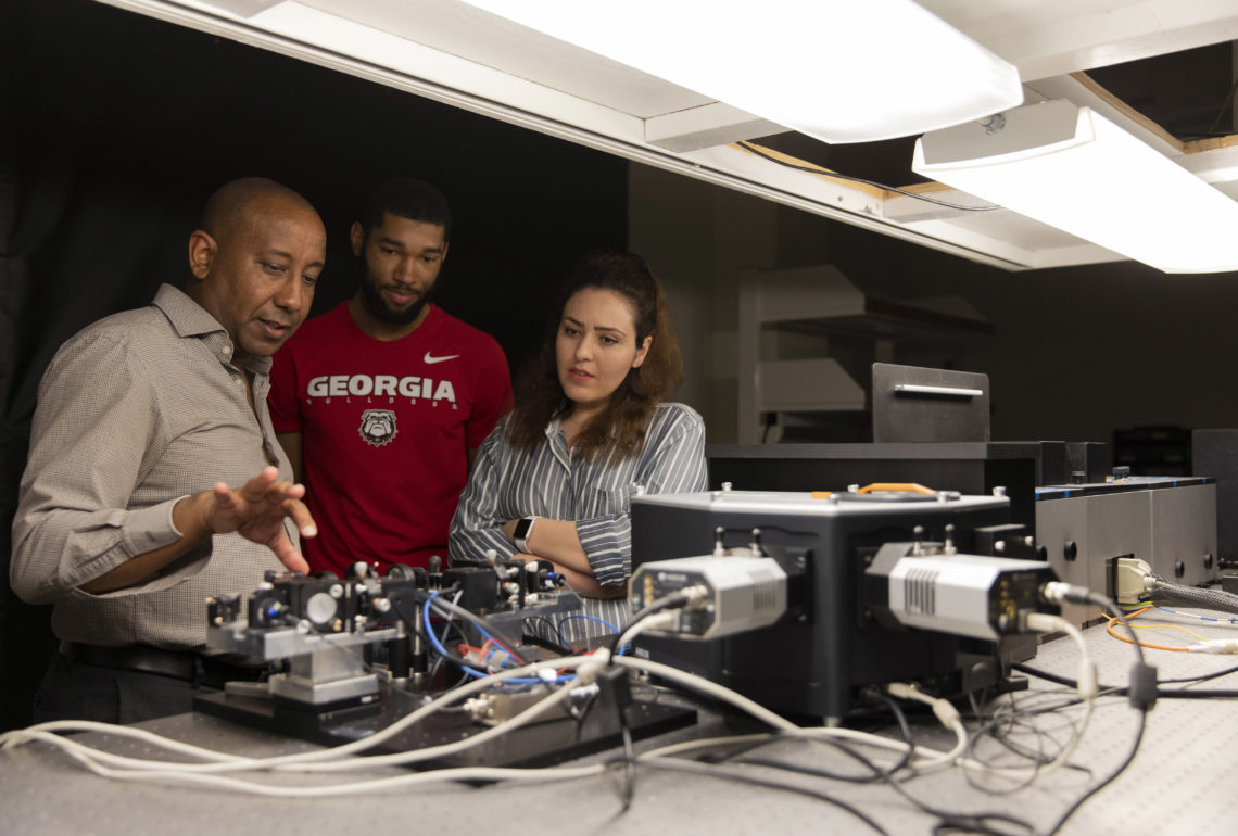 photo of three people with electronic equipment 