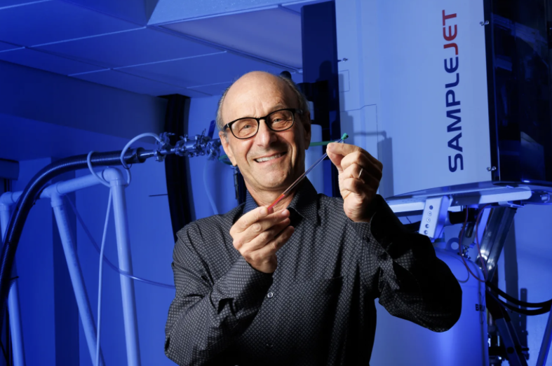 Photo of man in research lab, holding small thin tube.