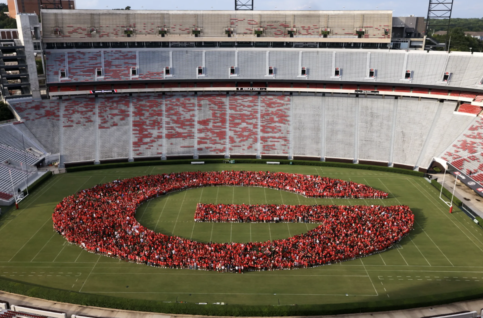photo of letter G formed by people in stadium, day
