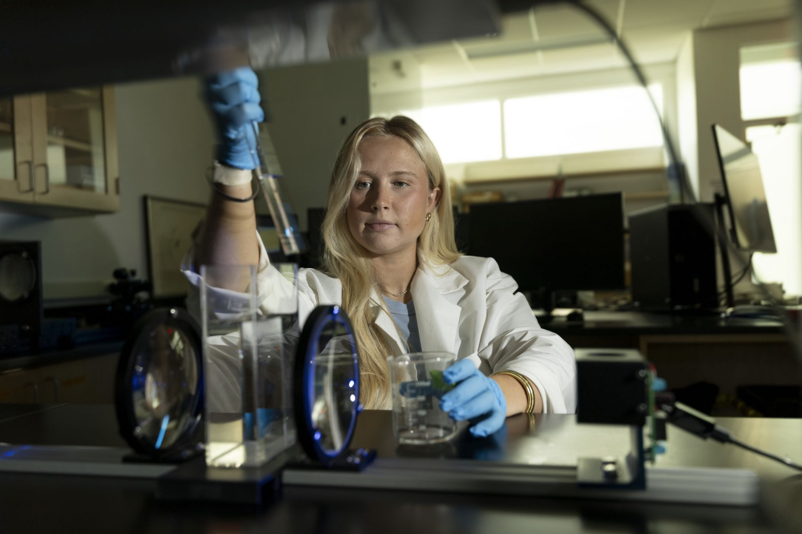 photo of woman in lab with instruments, white coat, pipette
