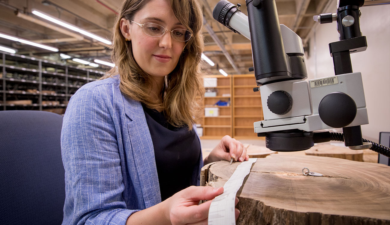 photo of woman with microscope and tree cookie