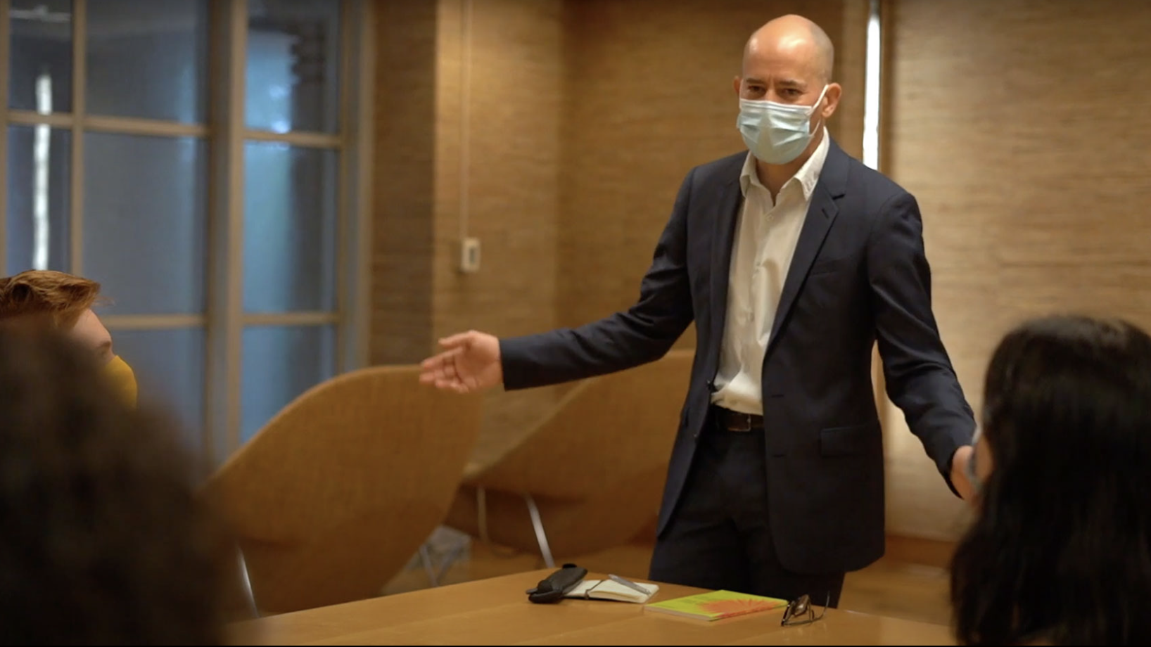 photo of man with mask standing at table, arms spread