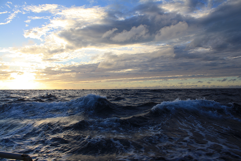 photo of breaking waves in ocean with clouds and sky