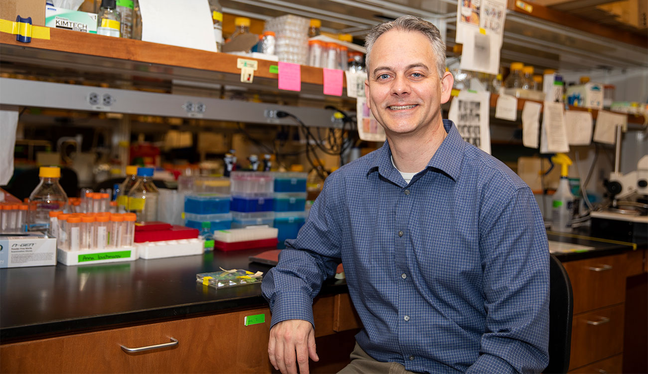 photo of man in lab, with table and lab equipment