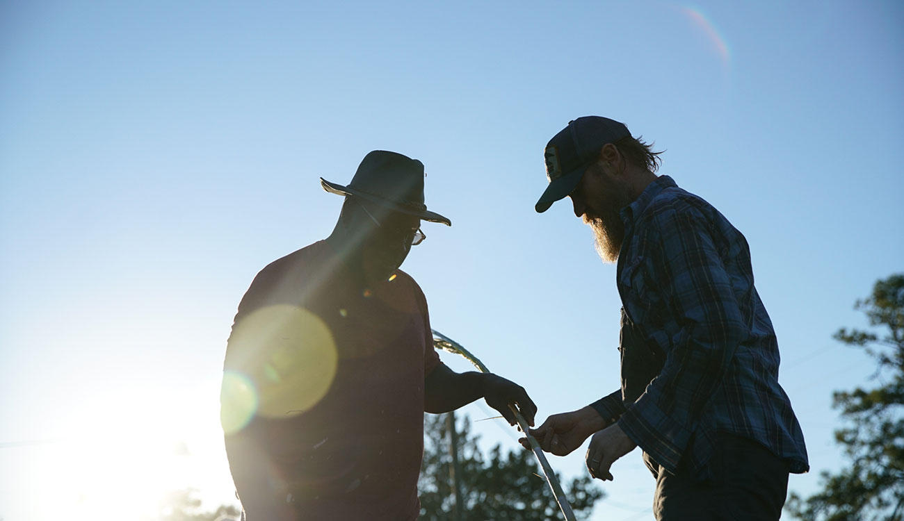 photo of two men, with stalk, sun, and sky