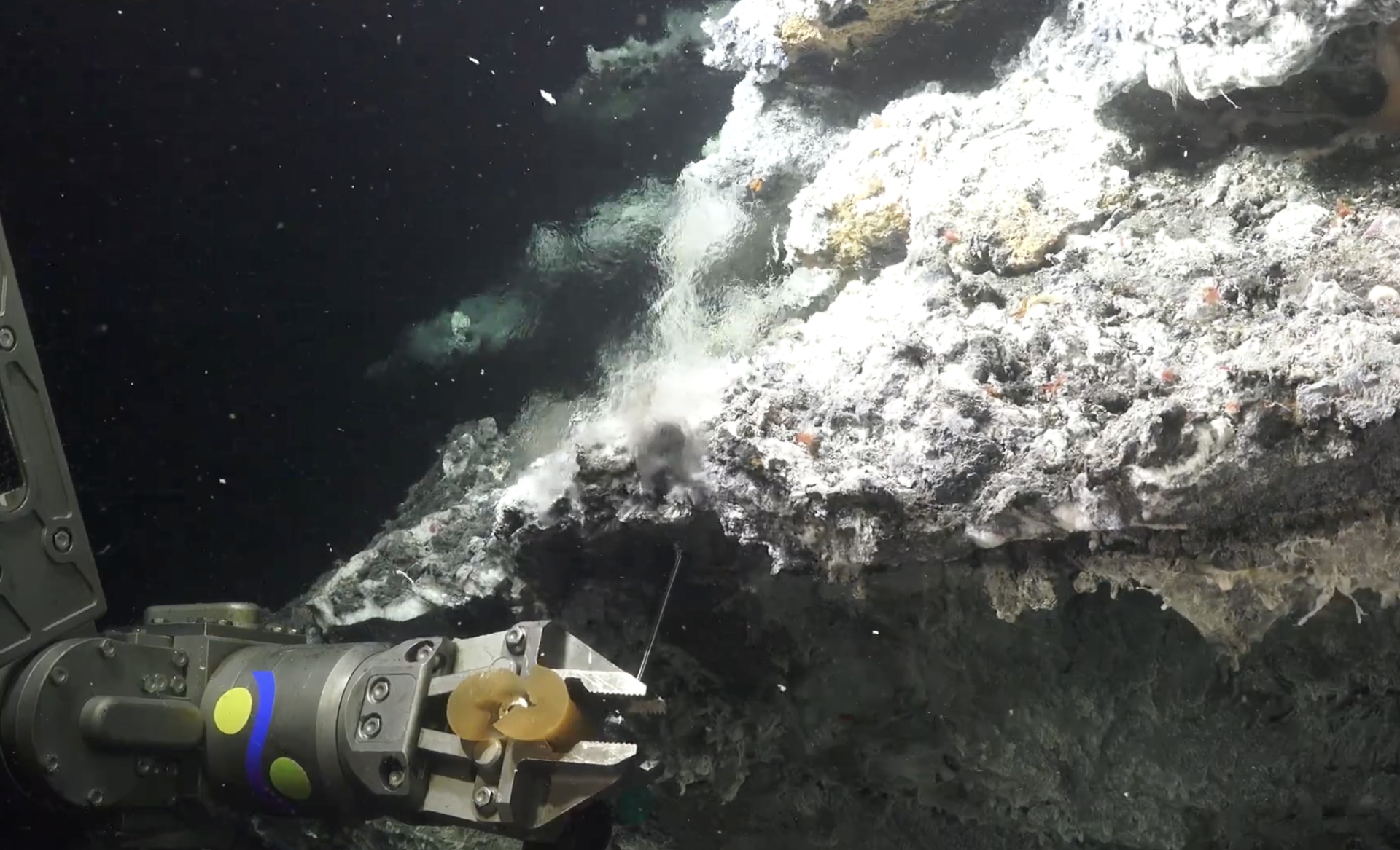 photo of smoke plume in water, mechanical arm in foreground